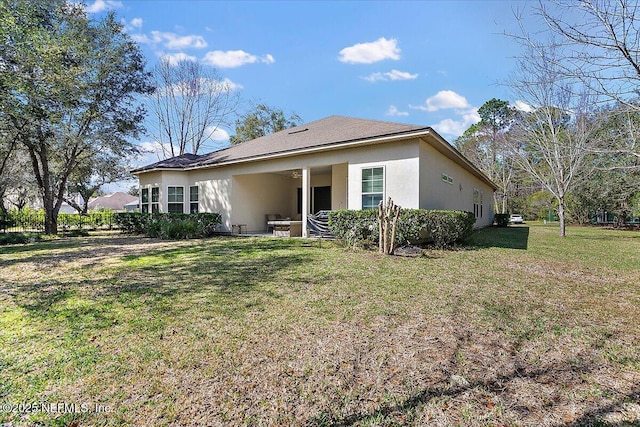 rear view of property with a lawn and stucco siding