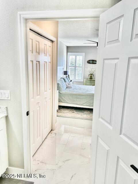 hall with a textured ceiling, marble finish floor, and a textured wall