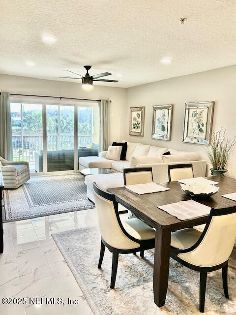 dining room with a textured ceiling, marble finish floor, and ceiling fan