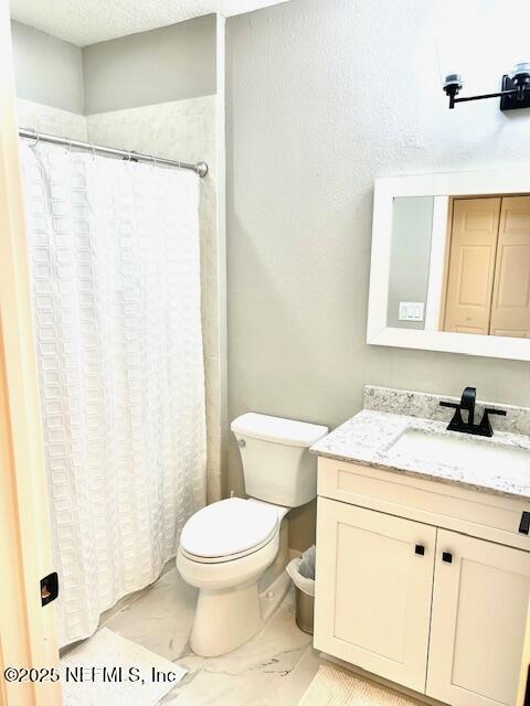 full bathroom with a textured ceiling, curtained shower, toilet, vanity, and marble finish floor