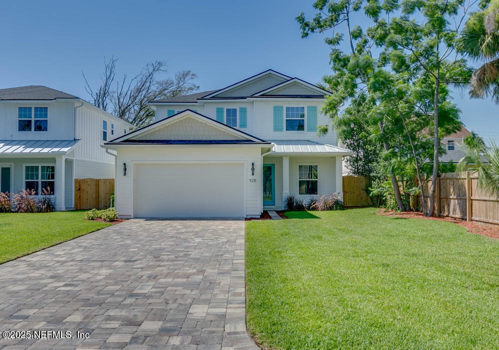 view of front of home with a front lawn, decorative driveway, an attached garage, and fence