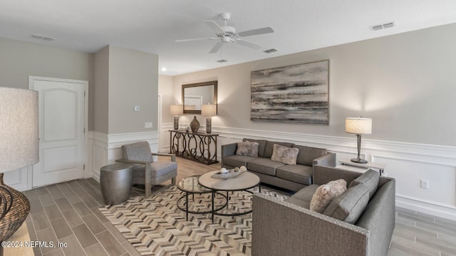 living room featuring a ceiling fan, wainscoting, visible vents, and wood tiled floor