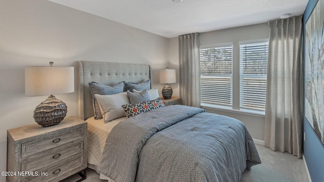 bedroom with light carpet, baseboards, and a textured ceiling