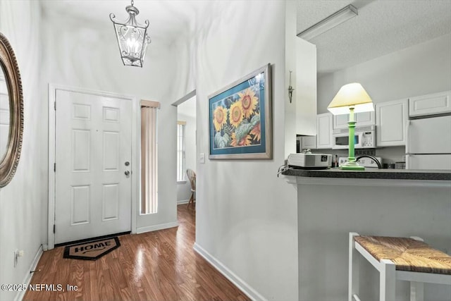 entrance foyer featuring a textured ceiling, wood finished floors, and baseboards