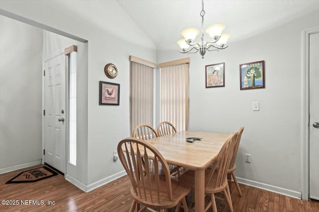 dining space with lofted ceiling, a notable chandelier, baseboards, and wood finished floors