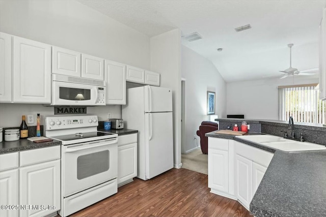 kitchen featuring dark countertops, visible vents, white cabinetry, a sink, and white appliances