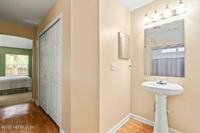 bathroom featuring a closet, visible vents, baseboards, and wood finished floors