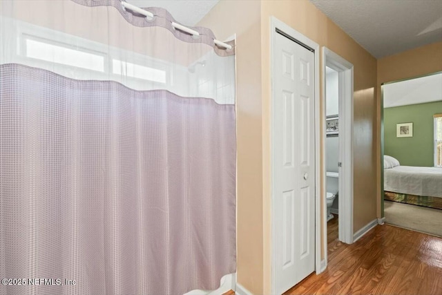 full bath featuring a shower with curtain, toilet, ensuite bath, and wood finished floors