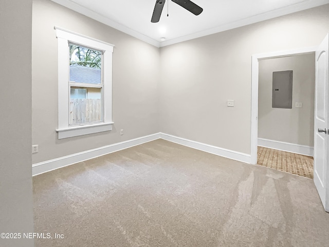 carpeted empty room featuring a ceiling fan, electric panel, crown molding, and baseboards