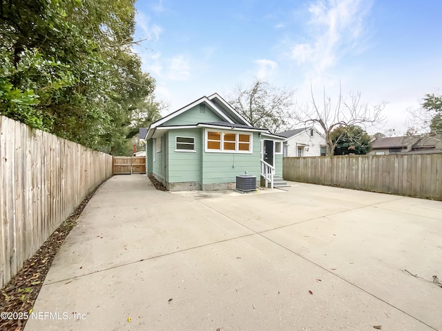 back of property with entry steps, a patio, a fenced backyard, crawl space, and central AC