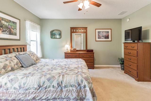 bedroom with ceiling fan, baseboards, a textured ceiling, and light colored carpet