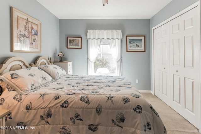 bedroom featuring light carpet, baseboards, and a closet