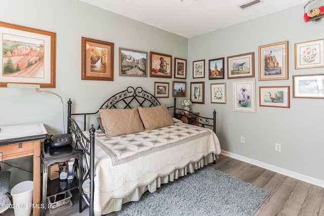 bedroom with visible vents, baseboards, and wood finished floors