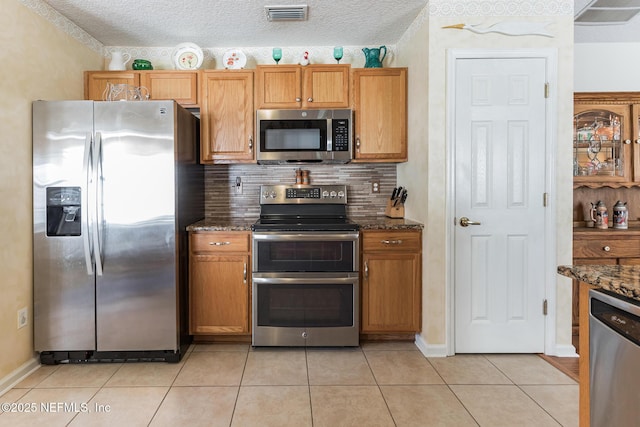 kitchen featuring light tile patterned floors, tasteful backsplash, visible vents, appliances with stainless steel finishes, and dark stone counters