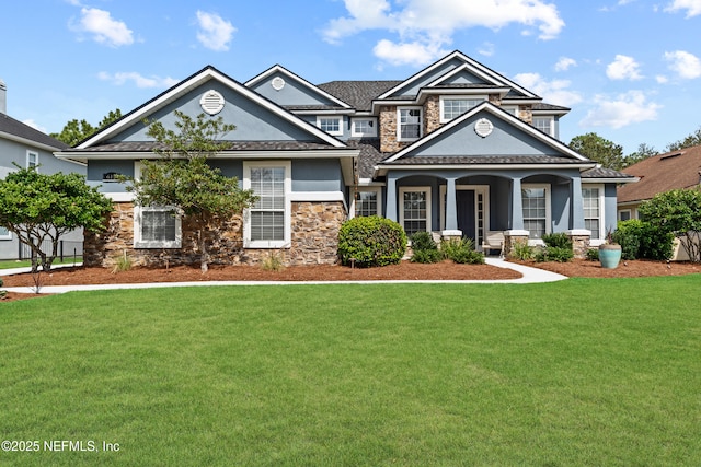 craftsman inspired home with stone siding, a front yard, and stucco siding