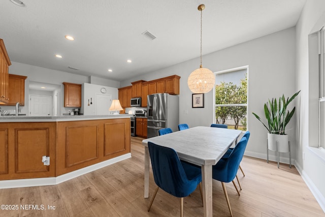 kitchen featuring visible vents, brown cabinetry, stainless steel appliances, light countertops, and light wood-style floors