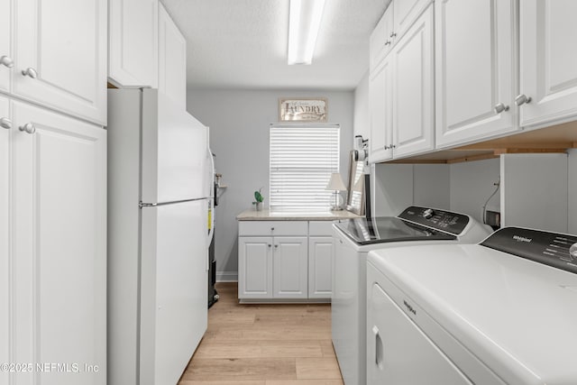 clothes washing area featuring light wood finished floors, washer and dryer, and a textured ceiling