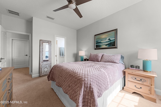 bedroom featuring visible vents, light carpet, and a textured ceiling