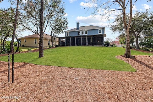 back of house with a sunroom, a yard, and a chimney