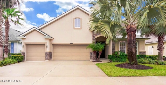 mediterranean / spanish-style home featuring a garage, stone siding, driveway, and stucco siding