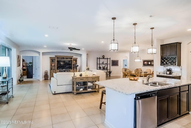 kitchen featuring decorative light fixtures, open floor plan, a kitchen island with sink, a sink, and dishwasher