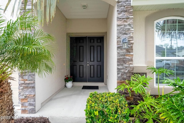 property entrance with stone siding and stucco siding