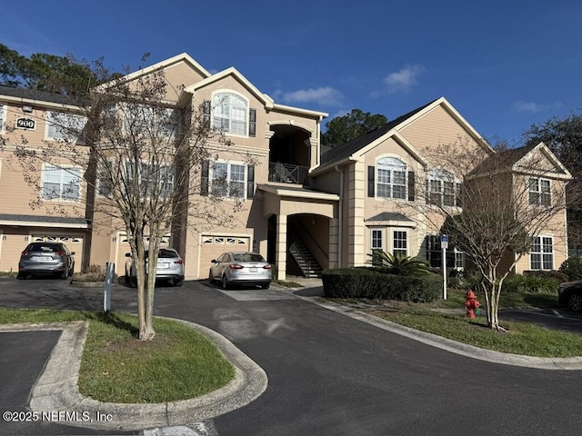 view of building exterior with a garage, driveway, and stairs