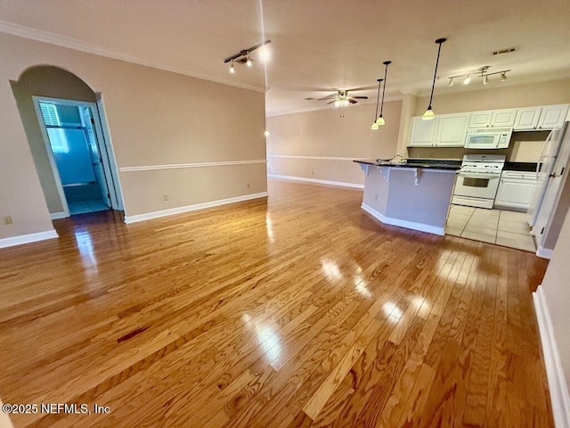 kitchen featuring white appliances, white cabinets, dark countertops, open floor plan, and hanging light fixtures