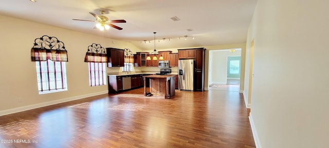 kitchen with a ceiling fan, stainless steel appliances, vaulted ceiling, open floor plan, and a center island