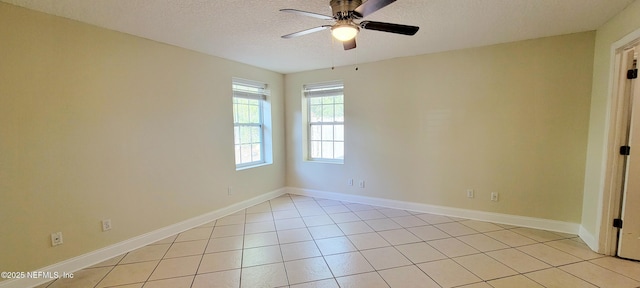 spare room featuring light tile patterned flooring, baseboards, and a textured ceiling