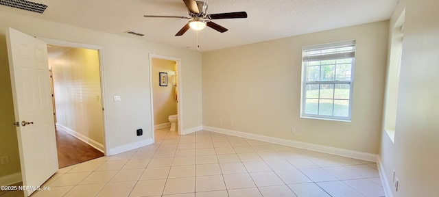 spare room featuring light tile patterned floors, visible vents, a textured ceiling, and ceiling fan