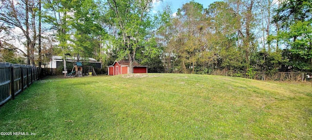 view of yard featuring a storage shed, an outdoor structure, a playground, and a fenced backyard