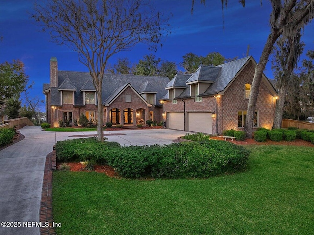 view of front facade with a garage, concrete driveway, fence, a front yard, and brick siding