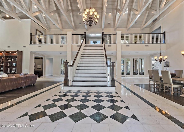 interior space with wood ceiling, stairway, beamed ceiling, a high ceiling, and a chandelier