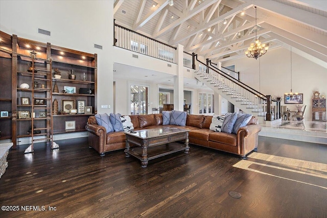 living room with beam ceiling, visible vents, wood finished floors, a chandelier, and stairs