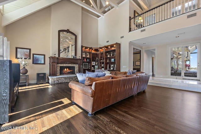 living area featuring dark wood-style flooring, visible vents, a fireplace, and beam ceiling