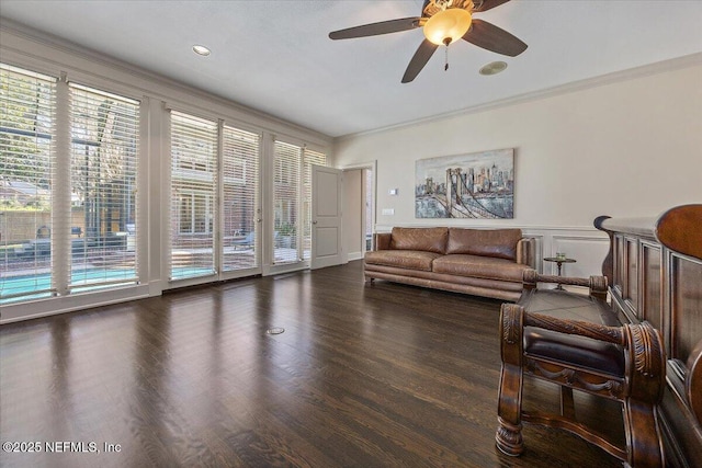 living room with a wainscoted wall, ornamental molding, dark wood-style flooring, and a wealth of natural light