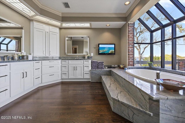 full bathroom featuring double vanity, visible vents, wood finished floors, crown molding, and a bath