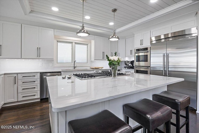 kitchen with a sink, white cabinetry, hanging light fixtures, appliances with stainless steel finishes, and a center island