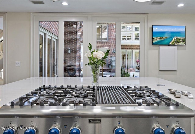 interior details with light stone countertops, visible vents, range, and recessed lighting