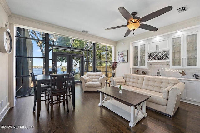 living room with visible vents, dark wood finished floors, a water view, crown molding, and french doors