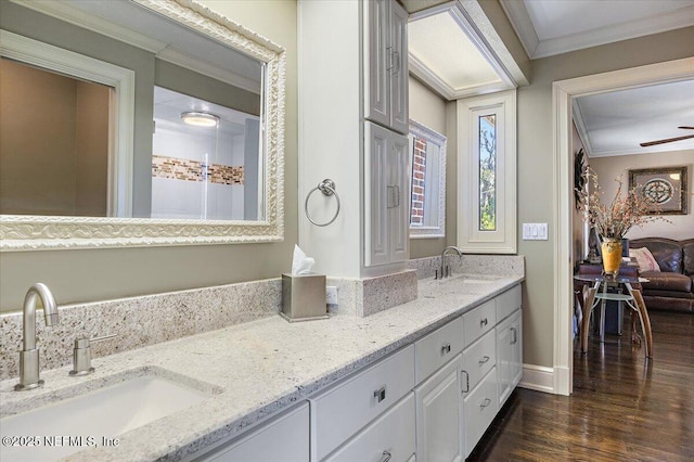 full bath with double vanity, crown molding, a sink, and wood finished floors