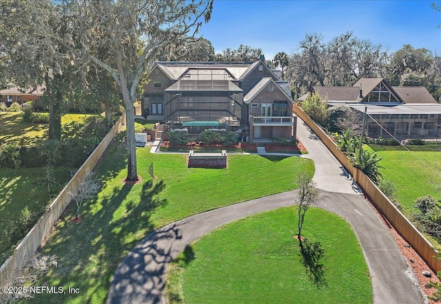 rear view of property with a lanai, fence, and a lawn