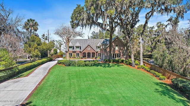 english style home featuring a front yard and fence