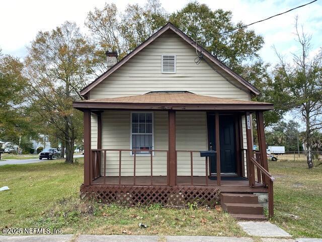 bungalow-style home with covered porch, a chimney, and a front yard