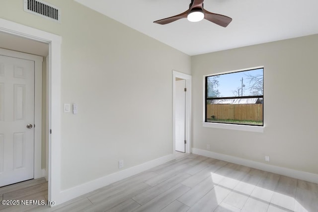 unfurnished room featuring ceiling fan, light wood finished floors, visible vents, and baseboards