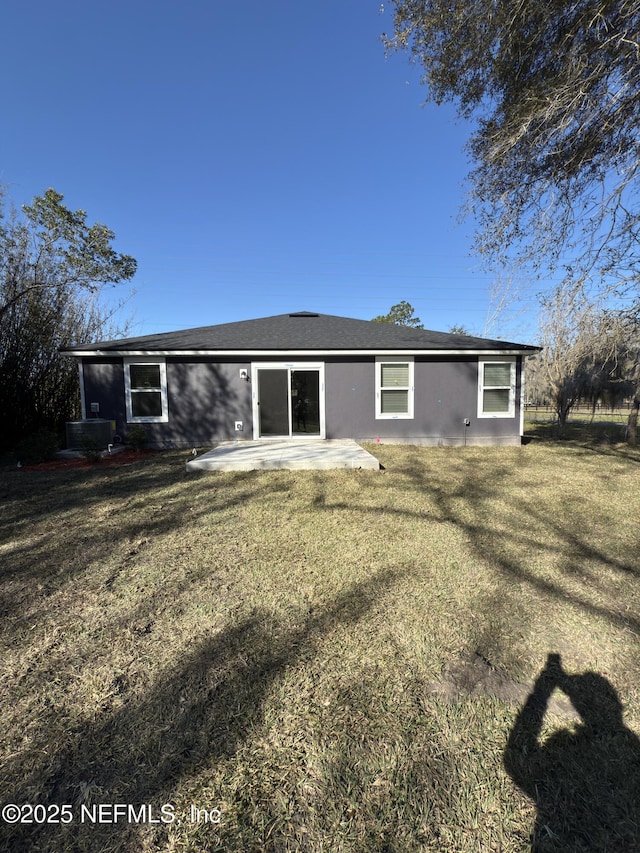 rear view of property featuring stucco siding, central AC unit, a lawn, and a patio