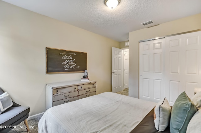 bedroom featuring baseboards, visible vents, a textured ceiling, carpet floors, and a closet