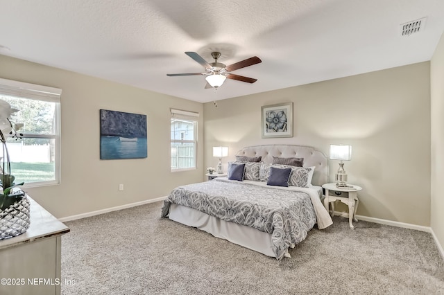 carpeted bedroom with visible vents, baseboards, and multiple windows