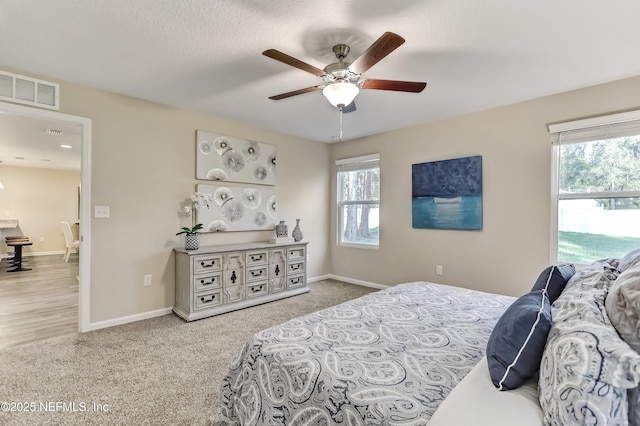 bedroom featuring ceiling fan, light colored carpet, visible vents, and baseboards